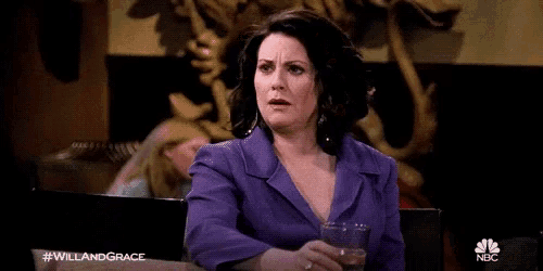 a woman in a purple jacket is sitting at a table with a glass of wine .