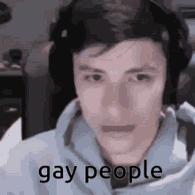 a young man wearing headphones and a hoodie with the words `` gay people '' on his face .