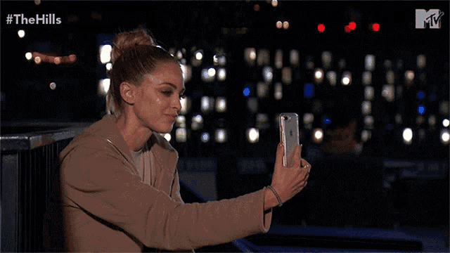 a woman is taking a picture of herself with a phone with the hills written on the bottom