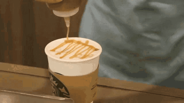 a starbucks coffee cup with a caramel drizzle on top of it .