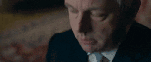 a close up of a man in a suit and tie making a face .