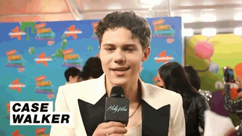 a young man is talking into a microphone while wearing a suit .