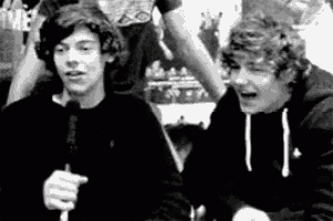two young men are sitting next to each other in a black and white photo . one of the men is holding a microphone .