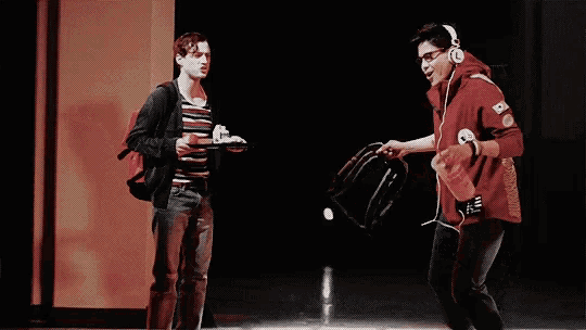 a man in a red hoodie is throwing a bottle of soda to another man .