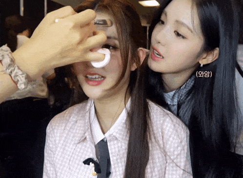 a woman applying makeup to another woman 's face with a sponge