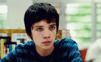 a young boy wearing a blue striped shirt is sitting in a library