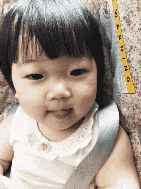 a baby in a car seat with a warning label