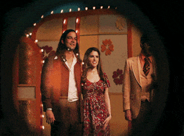 a woman in a red dress is standing next to a man in a suit
