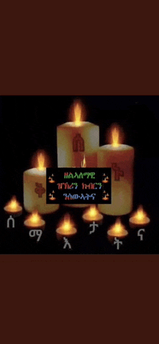 a bunch of lit candles are sitting on top of each other in a dark room .