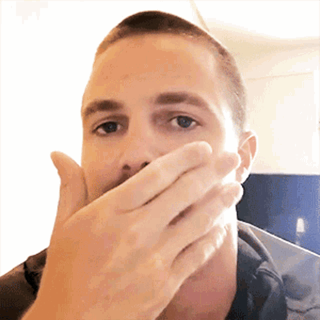 a man covering his mouth with his hand while looking at the camera