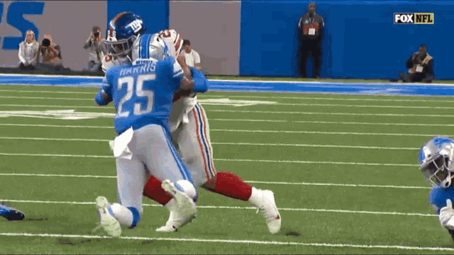 a football player with the number 25 on his jersey is being tackled by another player