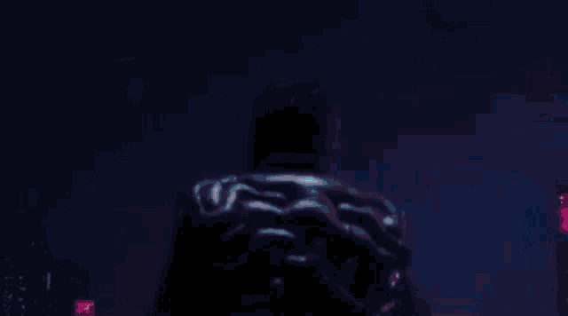 a man wearing a mask is standing in the dark .