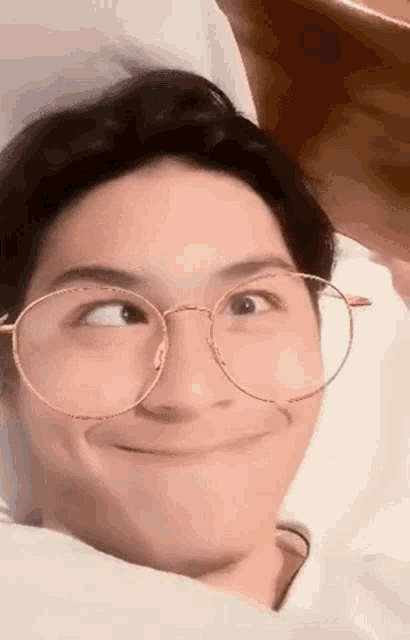 a close up of a person wearing glasses and making a funny face .