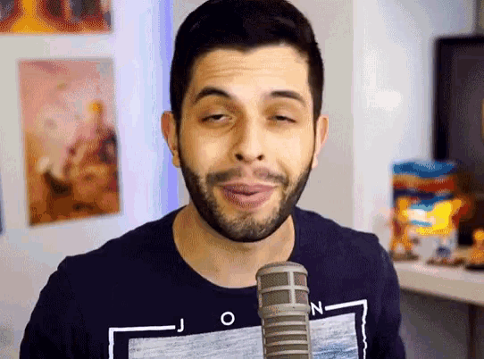 a man with a beard wearing a black shirt with the letter n on it