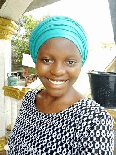 a woman wearing a turban and a black and white top smiles for the camera