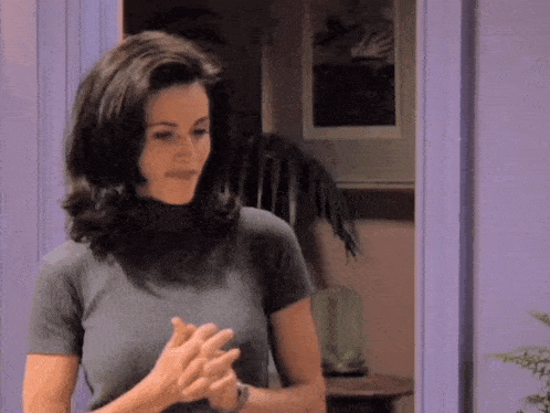 a woman is clapping her hands in front of a purple door in a room .