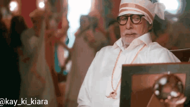 a man wearing glasses and a turban is sitting in front of a picture frame with the caption kay_ki_kiara