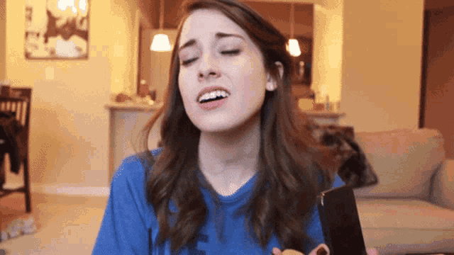 a woman wearing a blue shirt with the letter e on it is holding a cell phone