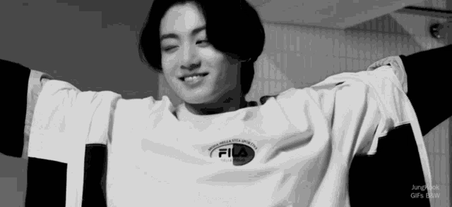 a black and white photo of a young man wearing a fila t-shirt .