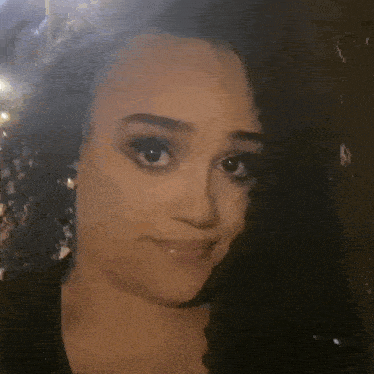 a close up of a woman 's face with curly hair making a face .