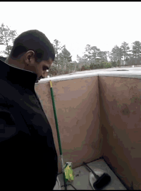a man in a black jacket is standing next to a mop and a spray bottle