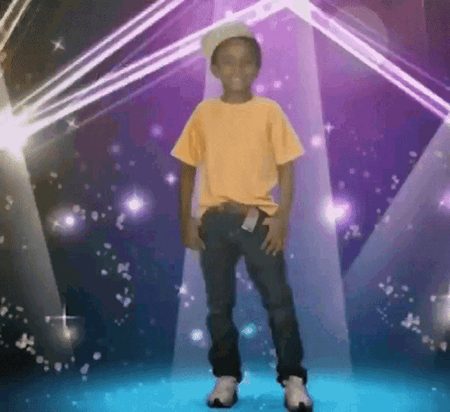a boy in a yellow shirt is standing in front of a stage