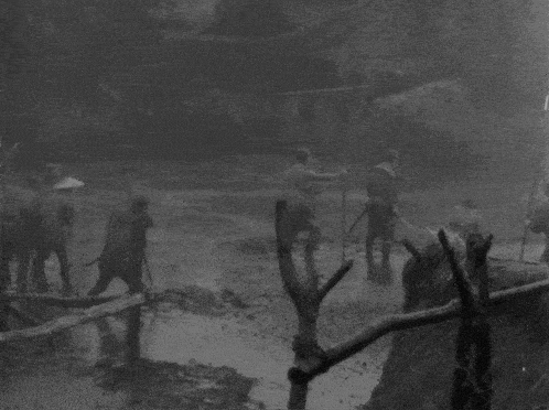 a black and white photo of a group of men standing in a muddy field