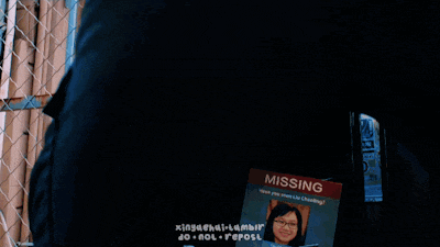 a person is standing in front of a chain link fence with a missing sign on their back
