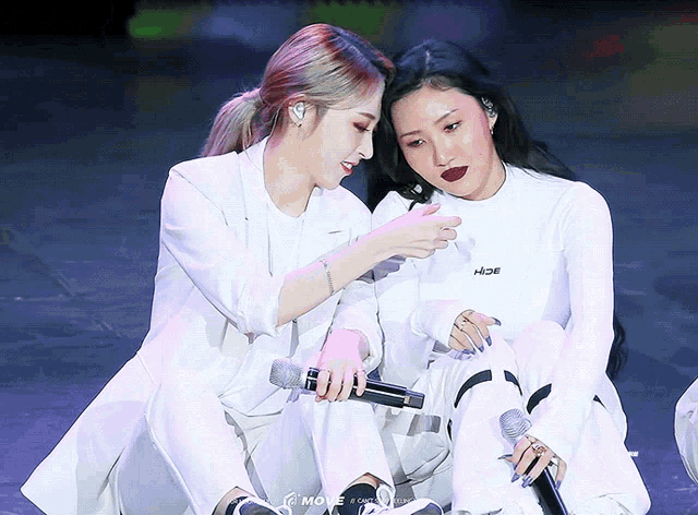 two women sitting next to each other with one wearing a white shirt that says moe on it