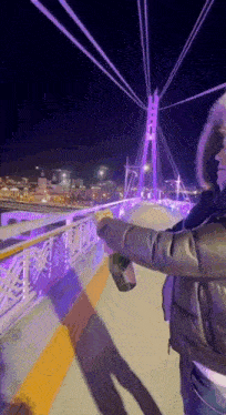 a person holding a bottle of beer on a bridge
