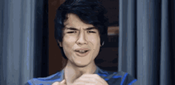a young man with black hair is making a funny face .