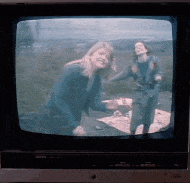 a tv screen shows two women having a picnic in the woods