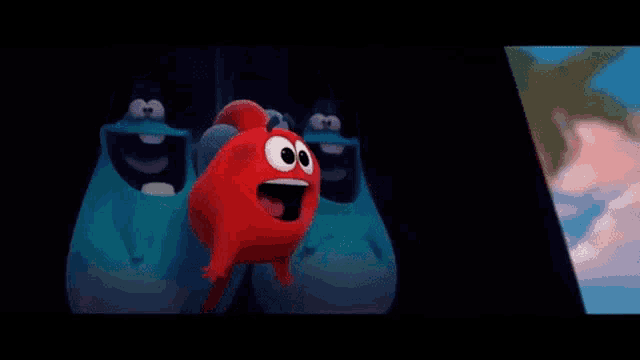 a red cartoon character with big eyes is standing next to a blue monster in a dark room .