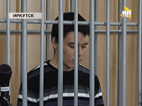 a man in a striped shirt is behind bars with a sticker that says " иркутск "