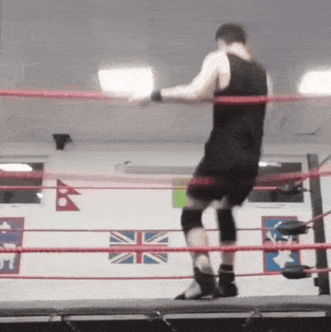 a man in a black tank top and shorts is standing in a boxing ring