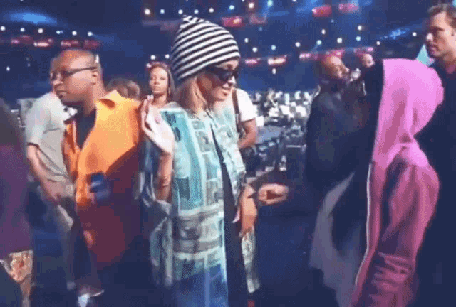 a woman wearing a striped hat is dancing in a crowd of people