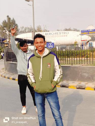 two young men are posing for a picture in front of an aero restro plane