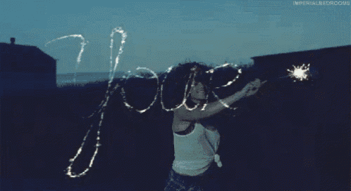 a woman is holding a sparkler and writing the word joors on the ground