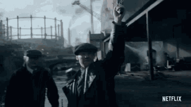 a man in a hat is holding a gun in his hand while walking down a street .