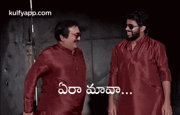two men in red shirts are standing next to each other and laughing in telugu .