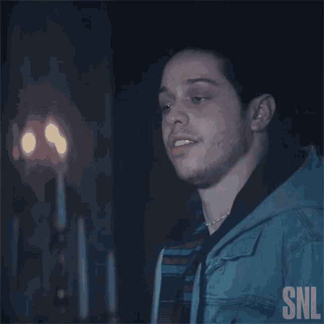 a man in a blue jacket is blowing a kiss while standing in front of candles .