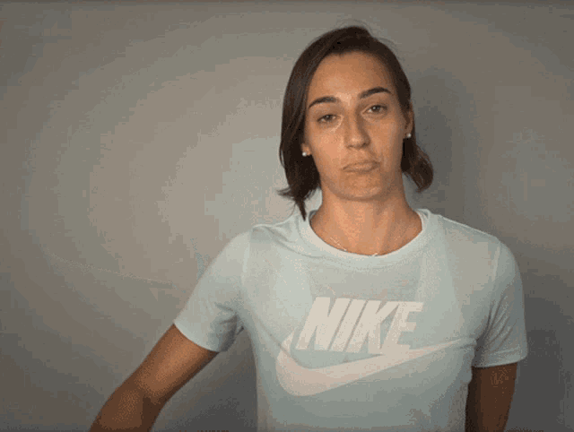 a woman wearing a light blue nike shirt makes a funny face
