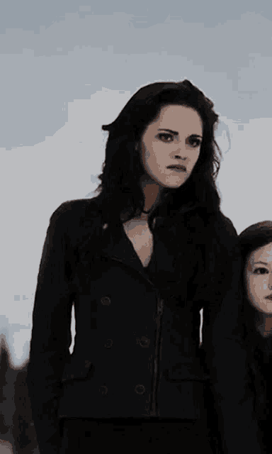 a woman in a black jacket stands next to another woman in a black jacket