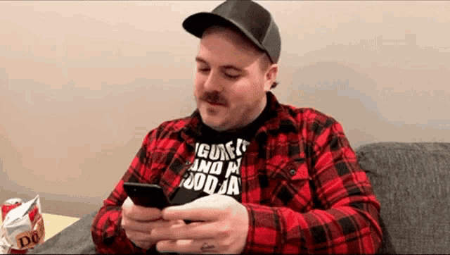 a man wearing a plaid shirt is looking at his phone