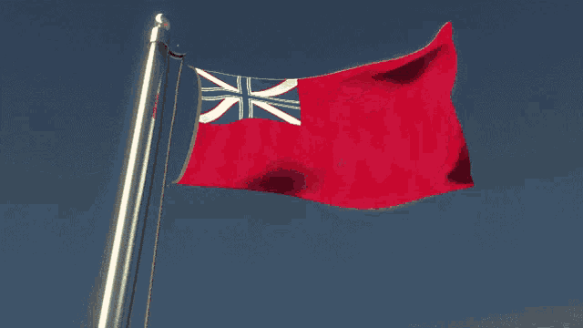 a red and white flag is flying in the wind on a flag pole