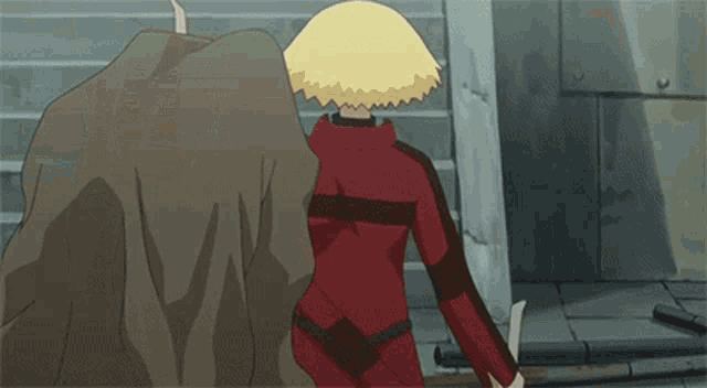 a person in a red jacket is standing next to a rock .