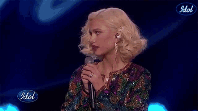 a woman in a sequined jacket is singing into a microphone .