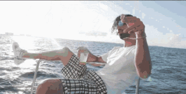 a man is sitting on a boat holding a shot glass
