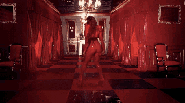 a woman in a red outfit stands in a hallway