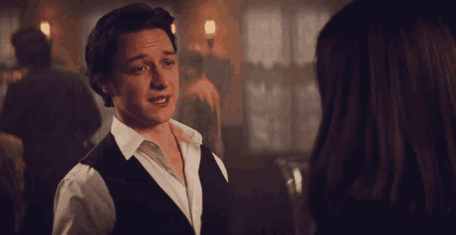 a man in a white shirt and black vest dancing with a woman